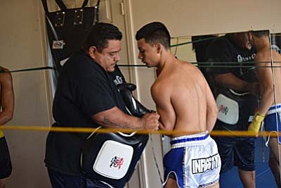 Trainer Guillermo Briseno helps fighter with gloves before sparing for Saturdays title fight. ( Photos by J.T. Keith)