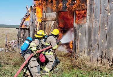 Photo/Mike MacPhee<br>

Ponderosa firefighters Sal Unale and Dan Coyle, make fire attack while training at a barn scheduled for demolition in Garland Prairie.
