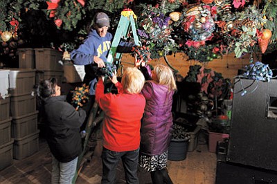Above: The Williams-Grand Canyon Chamber of Commerce’s Pimi Bennett, Jan Shirley and Gioia Goodrum hand chamber chairman Jim Winbourn Christmas decorations in preparation for the Mountain Village Holiday celebration. Ryan Williams/WGCN
