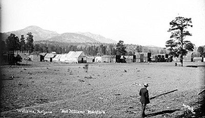 A man gazes over downtown Williams in 1883. Bill Williams Mountain is in the distance. Photo/Williams Library Historical Photo Archive