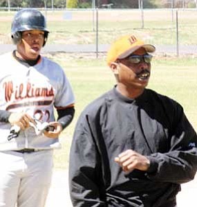 Coach Johnny Hatcher signals to the batter during a recent game as Tyrell Valdivia looks on.