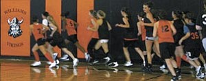 Players run laps around the Williams High School gymnasium in order to get warmed up prior to basketball practice.