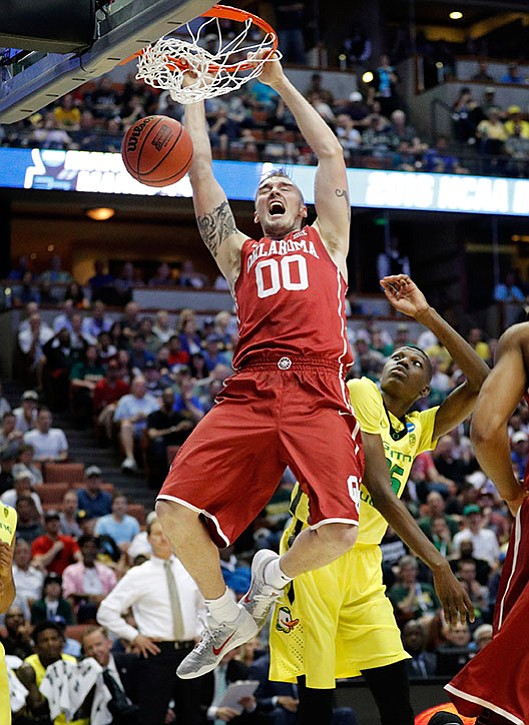 Oklahoma forward Ryan Spangler dunks over Oregon forward Chris Boucher during the first half of an NCAA college basketball game in the regional finals of the NCAA Tournament, Saturday, March 26, in Anaheim, Calif.