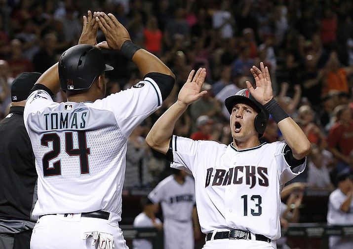 Arizona Diamondbacks' Nick Ahmed (13) and Yasmany Tomas (24) celebrate as both scored on a triple by Jean Segura during the sixth inning of a baseball game against the Colorado Rockies Tuesday, April 5, in Phoenix. 