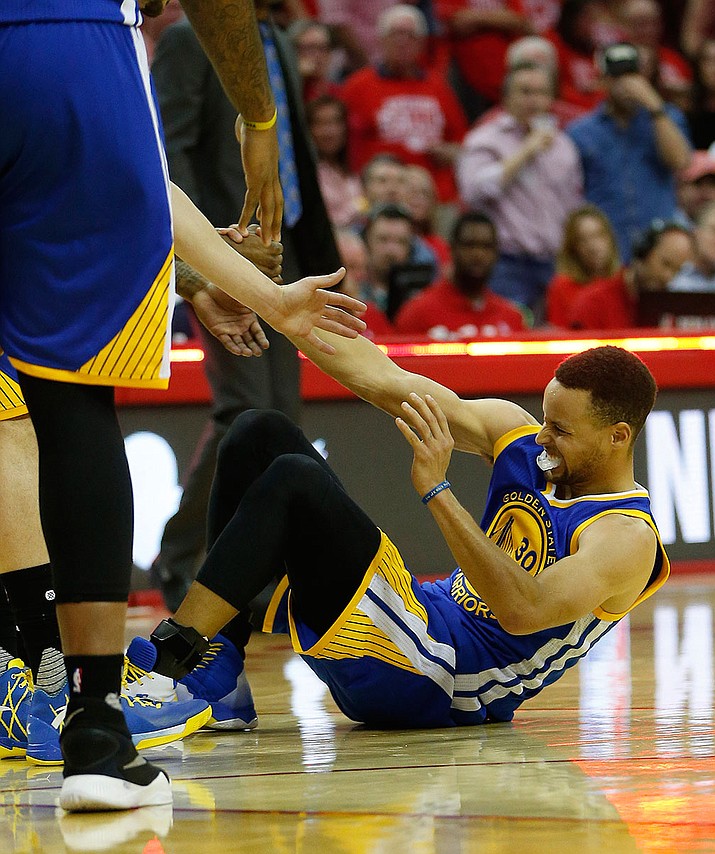 Golden State Warriors guard Stephen Curry is helped up April 24 after being injured on the final play before half during Game 4 in the first round of the NBA playoff series against the Houston Rockets, in Houston. 
