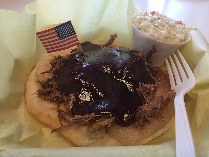 All American Fried Bread’s menu item Baby Ray’s Way is covered in barbecue pulled pork and comes with a side of coleslaw. 