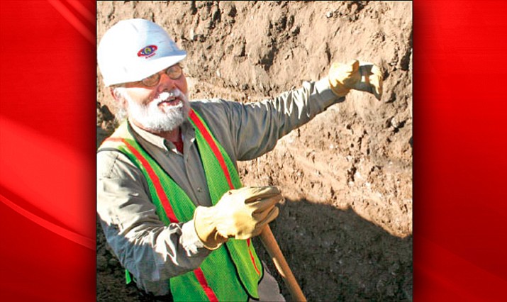 Archaeologist Fred Kraps describes where a midden, a compacted ancient layer of garbage, begins to widen within the walls of a new water line trench along Highway 69 through a prehistoric site.