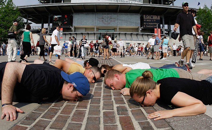Race fans lie down and kiss the yard of bricks at the Indianapolis Motor Speedway before the 93rd running of the Indianapolis 500 auto race in Indianapolis. The 100th running of the Indy 500 is Sunday, May 29. 
