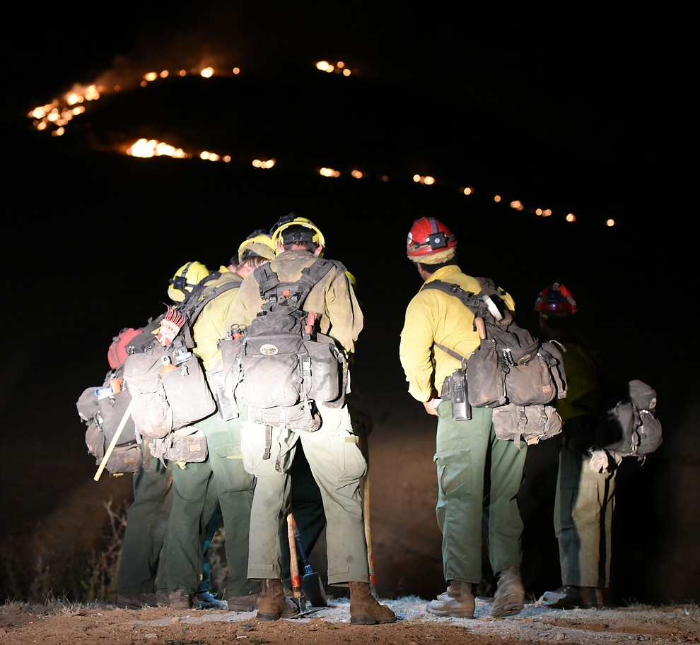 Truckee Hotshots watch the fire behavior and program their radios before heading uphill as Central Arizona Fire and National Forest firefighters worked to contain a wildland fire northeast of Coyote Springs Road and Pronghorn Lane in Prescott Valley Thursday night. (Les Stukenberg/The Daily Courier)