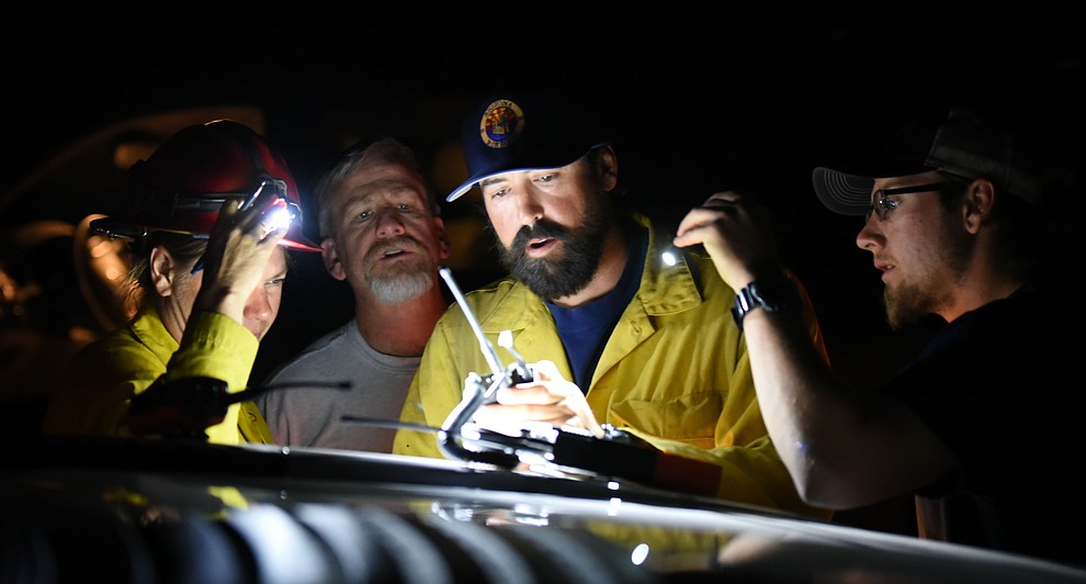Fire fighters check their radios as Central Arizona Fire, Truckee Hotshots and National Forest firefighters worked to contain a wildland fire northeast of Coyote Springs Road and Pronghorn Lane in Prescott Valley Thursday night. (Les Stukenberg/The Daily Courier)