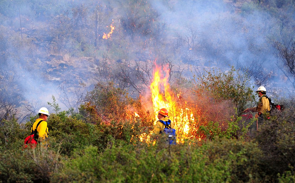 Fire crews work hot spots as fire burns through the hills on the south side of Yarnell Wednesday afternoon. (Les Stukenberg/The Daily Courier)