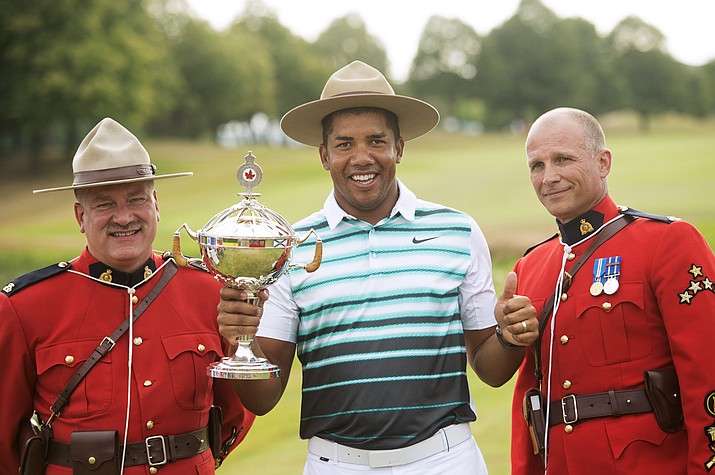 Jhonattan Vegas of Venezuela holds up the trophy as he celebrates winning the Canadian Open golf tournament, between two Mounties, Sunday, July 24, in Oakville, Ontario.
