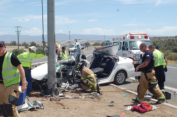 Rescue crews work to clean up the scene of a single-vehicle crash at Willow Creek Road and Pioneer Parkway late Sunday morning, July 24, while paramedics prepare the driver for air-transport to the hospital.