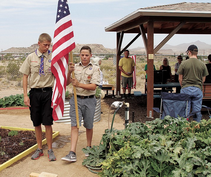 Eagle Scout Garrett Hoffman (holding the flag) and Brendon Allred perform a flag ceremony on Saturday next to the ramada they built.