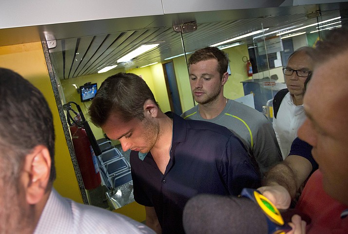 American Olympic swimmers Gunnar Bentz, center left, and Jack Conger, center right, leave the police station at Rio International airport early Thursday Aug. 18, 2016. The two were taken off their flight from Brazil to the U.S. on Wednesday by local authorities amid an investigation into a reported robbery targeting Ryan Lochte and his teammates. According to their lawyer they will not be allowed to leave Brazil until they provide testimony about the robbery. 