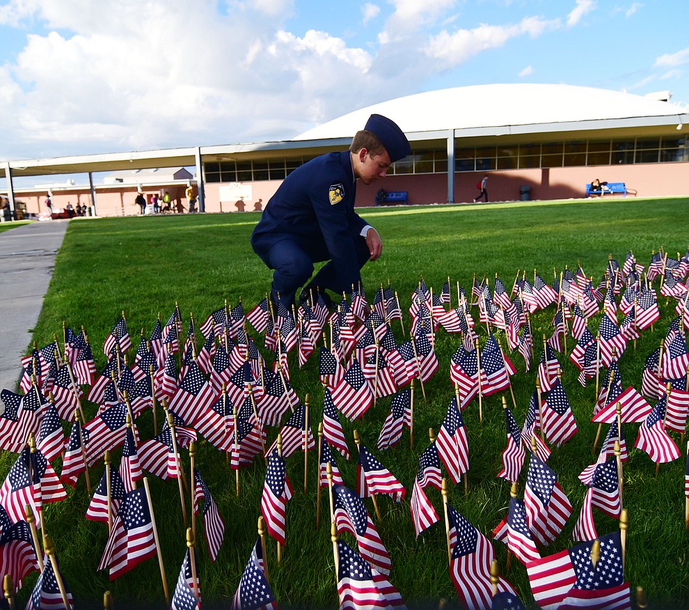 Prescott High School AFJROTC cadet Tobias Buettner straightens some of the flags represetning those lost in the 9/11 terrorist attacks before a 9/11 Remembrance ceremony Monday morning at Prescott High School.  (Les Stukenberg/The Daily Courier)