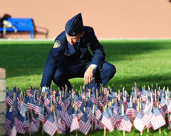 Prescott High School AFJROTC cadet Tobias Buettner straightens some of the flags represetning those lost in the 9/11 terrorist attacks before a 9/11 Remembrance ceremony Monday morning at Prescott High School.  (Les Stukenberg/The Daily Courier)