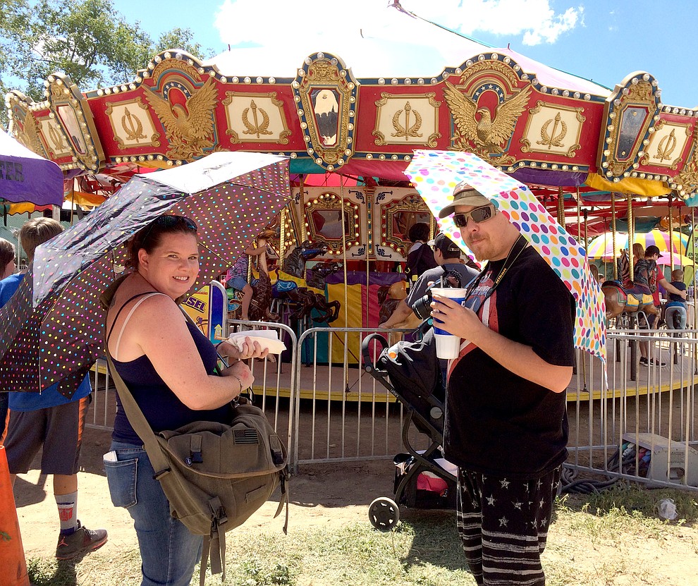 Jennifer and Daniel Lewis enjoy the sunny weather and a hotdog at Saturday's Yavapai County Fair while they wait for their daughters, Rachel and Cheyenne, riding the Merry-Go-Round. Rachel, 10, joined 4-H this year and her rabbit won the Reserve Champion ribbon.