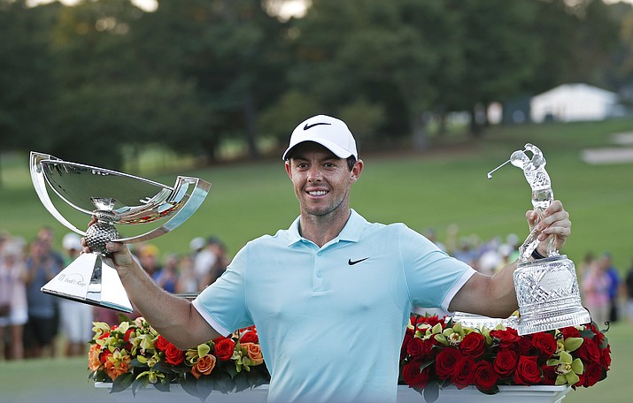Rory McIlroy poses with the trophies after winning the Tour Championship golf tournament and FedEX Cup at East Lake Golf Club  Sunday, Sept. 25, in Atlanta.