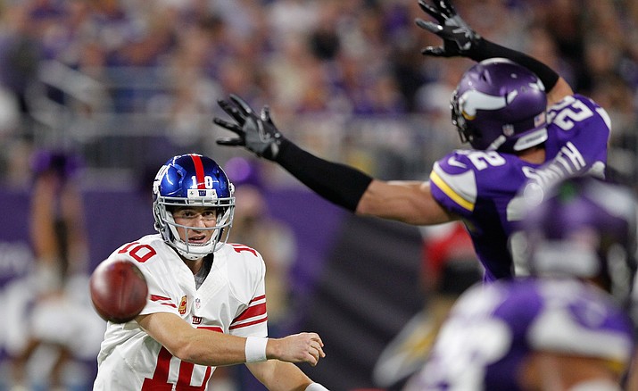 New York Giants’ Eli Manning throws a pass around Minnesota Vikings free safety Harrison Smith during their game Monday, Oct. 3. 
