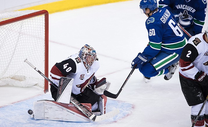 Arizona Coyotes' goalie Justin Peters, left, makes the save as Vancouver Canucks' Markus Granlund, of Finland, jumps in front of him during the third period of a preseason NHL hockey game in Vancouver, British Columbia, Monday, Oct. 3.