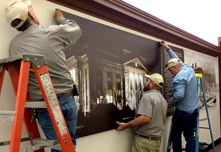 Yavapai County Facilities employees, from left, carpenters Frank Nez and Gerry Kring, and supervisor Terry Vallely, install  photograph panels with historic timeline information Oct. 4 on the ground floor of the Yavapai County Courthouse in preparation for the Courthouse Centennial Celebration Oct. 15.