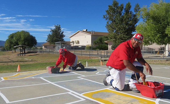 Pastor Don with Mountain Valley Church of God and B&M painting perform a service project at Coyote Springs Elementary, with help from a  Sherwin Williams donation, to re-paint maps on the playground.