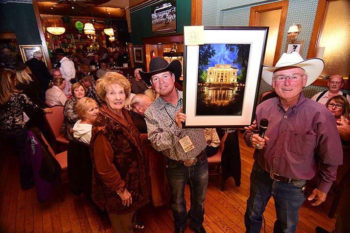 Joan, Mark and Tommy Meredith show off one of the many live auctions items available at the Friends of Jersey Lilly 2016 Courthouse Christmas Lighting Fundraiser Kick-Off Party Thursday night in Prescott.