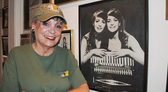 Terrie Frankel, Verde Valley Military Park committee member, poses next to a picture of herself and twin sister, Jennie, during their Doublemint Twin days. Frankel, a former Vietnam USO performer, said the park is “absolutely marvelous” and looks forward to the Nov. 11 ribbon-cutting at Garrison Park in Cottonwood. (VVN/Jennifer Kucich)