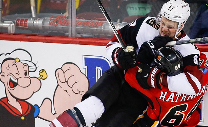 Arizona Coyotes' Lawson Crouse, left, fights with Calgary Flames' Garnet Hathaway during the second period of an NHL hockey game Wednesday, Nov. 16, in Calgary, Alberta.