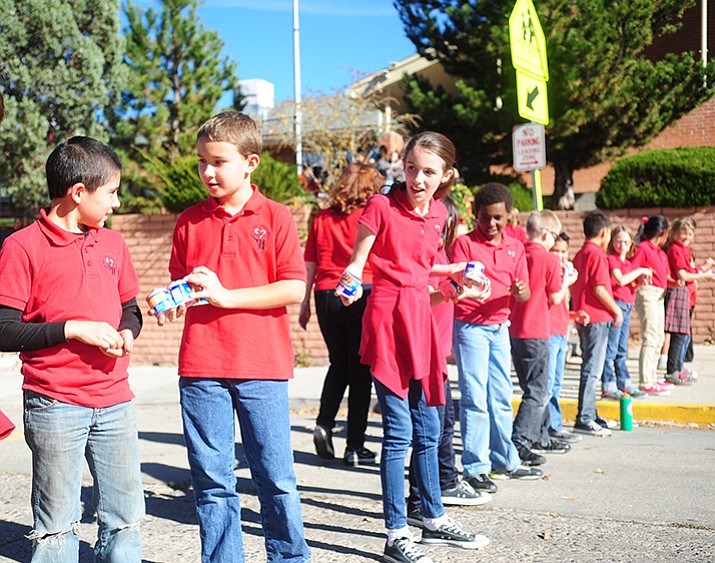 Students from the Sacred Heart School in Prescott create a human food chain to pass the canned goods across the street following their annual canned food drive on November 19, 2016. (Les Stukenberg/Courier)