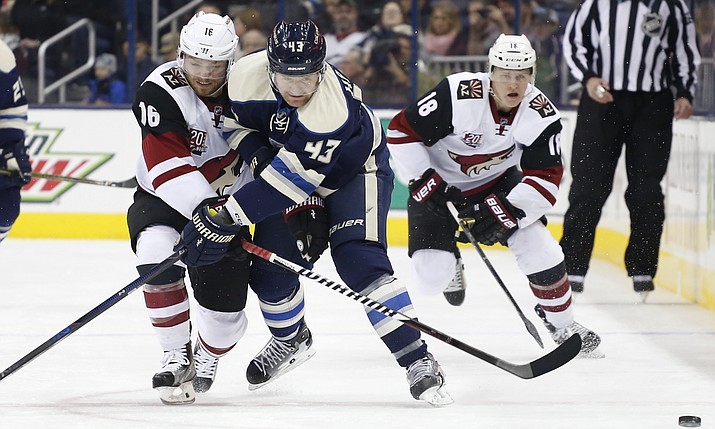 Arizona Coyotes’ Max Domi, left, and Columbus Blue Jackets’ Scott Hartnell, center, fight for a loose puck as Christian Dvorak follows the play during the first period of an NHL hockey game, Monday, Dec. 5, 2016, in Columbus, Ohio.