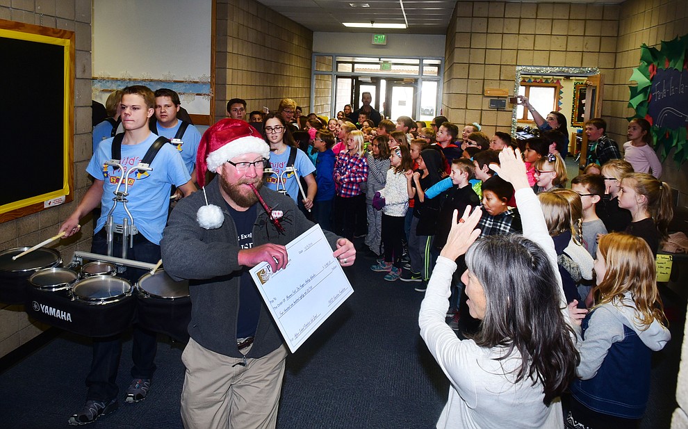 Prescott Unified School District Superintendent Joe Howard shows the $4980 check to students as they march with a drumline at Abia Judd as members of the Prescott Education Foundation went around on Friday, December 9 to district schools and handed out checks to teachers who had applied and received grants for special projects. (Les Stukenberg/The Daily Courier)