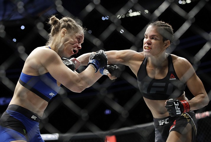 Amanda Nunes, right, connects with Ronda Rousey in the first round of their women's bantamweight championship mixed martial arts bout at UFC 207, Friday, Dec. 30, 2016, in Las Vegas. Nunes won the fight after it was stopped in the first round. 
