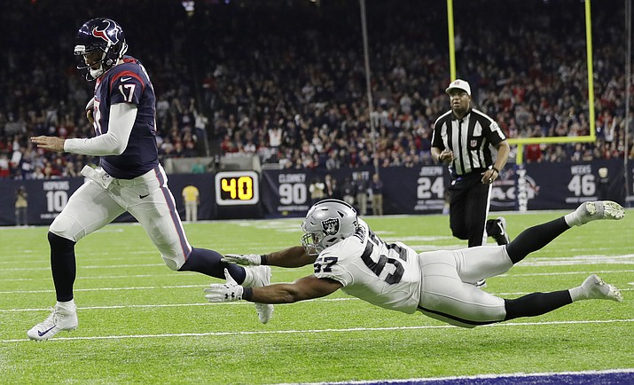Houston Texans quarterback Brock Osweiler scores on a two-yard run against Oakland Raiders' Cory James during their AFC Wild Card NFL football game Saturday, Jan. 7, in Houston. (Eric Gay/The AP)