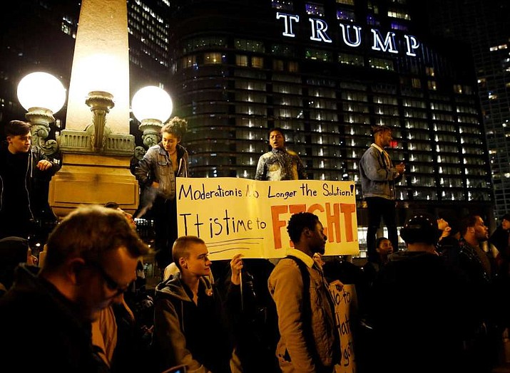 FILE - In this Nov. 10, 2016 file photo, protesters gather in downtown Chicago as they protest the election of President-elect Donald Trump across from the Trump hotel tower. Two Chicago street signs honoring President Donald Trump pulled down after the then-candidate characterized the city as a "war zone" have gone missing a city official said. One Trump sign does remain in Chicago: the 20-foot-tall letters that spell the president's name on the side of his hotel tower along the Chicago River. 