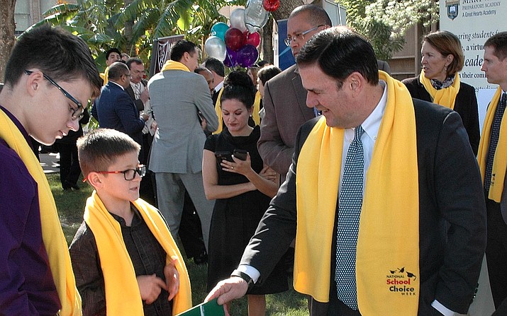 Gov. Doug Ducey gets briefed Thursday by 11-year-old Gabriel Burgess, a seventh grader in the Ajo Unified School District about a project his school is showing off at the Capitol for School Choice Week.  (Capitol Media Services photo by Howard Fischer)