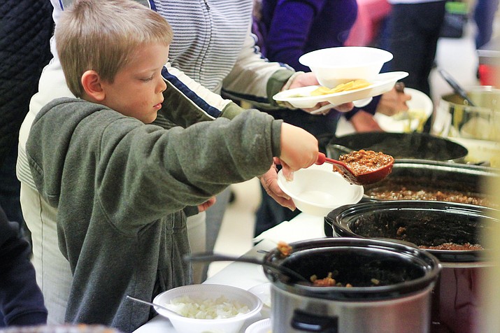 Alex Brigman serves up a bowl of chili at the St. Joseph church's annual chili cookoff.