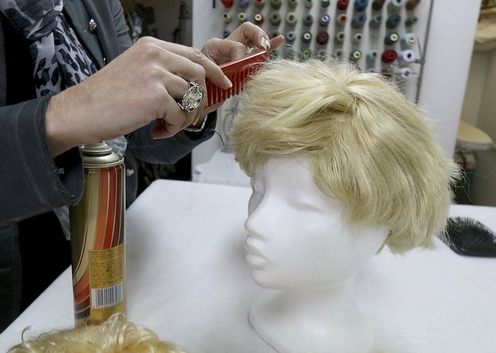Manuela Plank owner of a costume rental shop fashioning normal blond hairpieces into Trump wigs in Pfaffstaetten, Austria, Monday, Feb. 20, 2017. Just about everyone wants to be Donald Trump this carnival season in Austria -- so much so that some costume rentals are out of stock of wigs miming the U.S. president's signature hairstyle. (AP Photo/Ronald Zak)