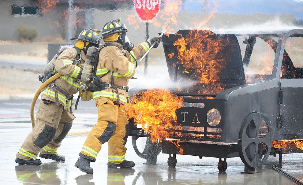 Jace Hall handles the nozzle and Russell Smith opens the hood as new Central Arizona Fire & Medical Authority firefighters do their final academy drill in front of friends and family Wednesday, February 22 in Prescott Valley. The vehicle fire prop was built for $4500. with the help of Barrett Propane, to purchase a fully built prop the cost would have been almost $40,000. (Les Stukenberg/The Daily Courier)