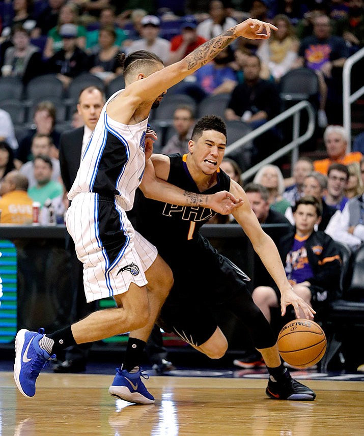 Phoenix Suns guard Devin Booker drives around Orlando Magic guard Evan Fournier during their NBA game Friday, March 17.