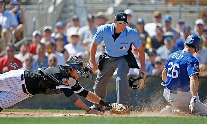Los Angeles Dodgers' Chase Utley (26) scores a run ahead of a diving tag-attempt by Chicago White Sox catcher Kevan Smith, left, as umpire Quinn Wolcott, center, watches during the first inning of a spring training baseball game Saturday in Glendale, Ariz.

