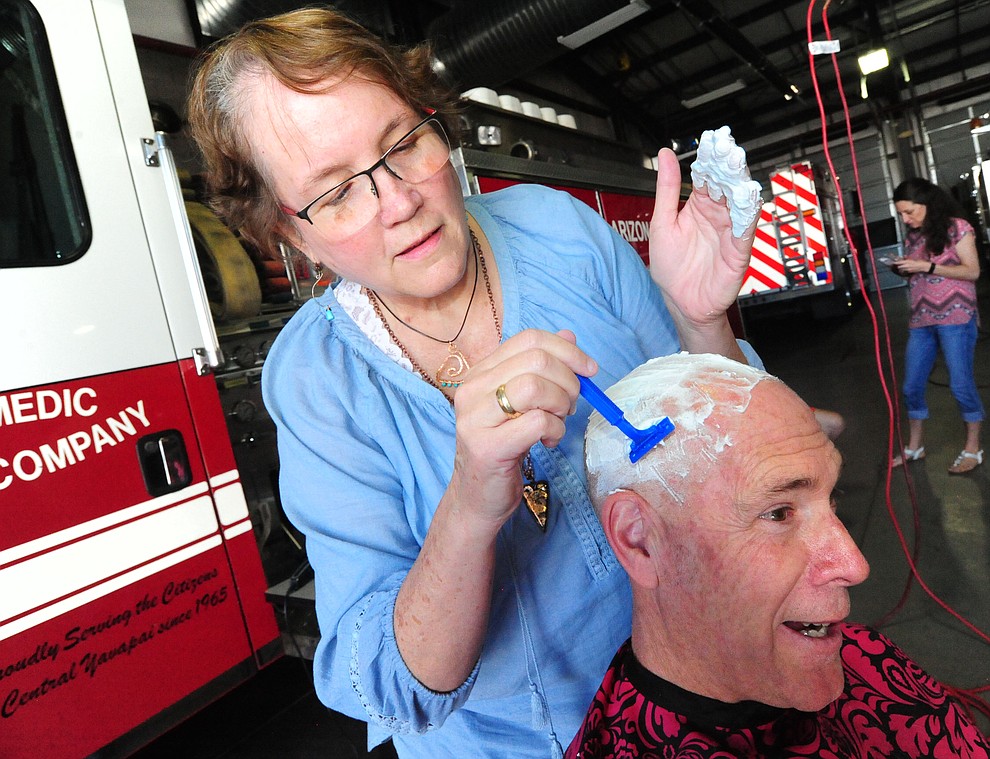 Patty Brookins shaves the head of Capt. Brian Burch as Central Arizona Fire & Medical firefighters shave their heads to support their Human Resources Manager Brookins Saturday, March 18 in Prescott Valley.