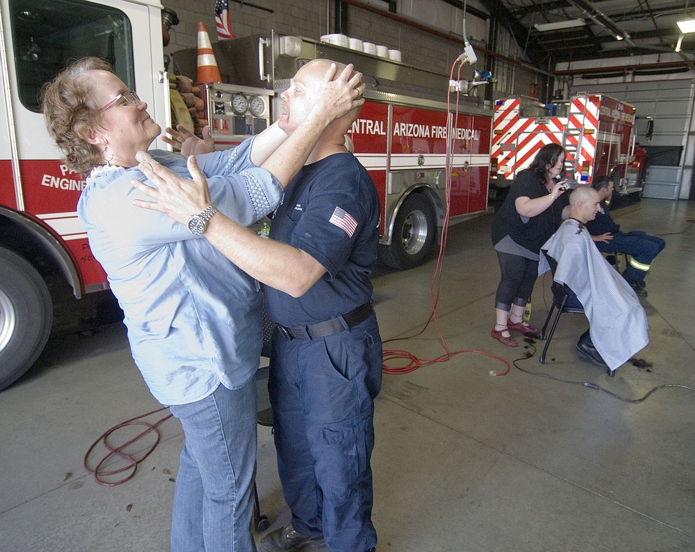 Patty Brookins feels Capt. Mark Mauldin's head as Central Arizona Fire & Medical firefighters shave their heads to support their Human Resources Manager Brookins Saturday, March 18 in Prescott Valley.