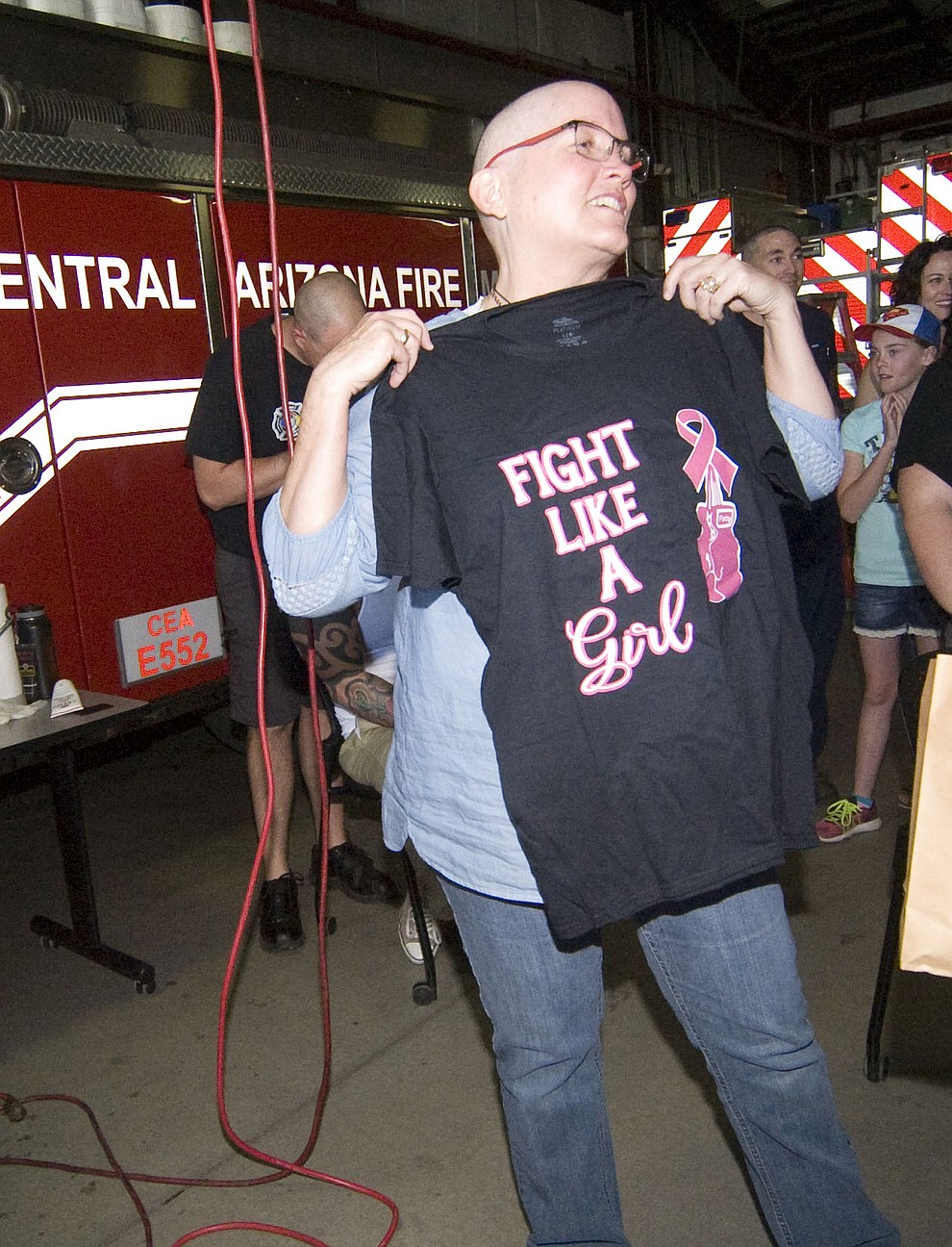 Patty Brookins holds up a shirt she was given as a gift as Central Arizona Fire & Medical firefighters shave their heads to support their Human Resources Manager Brookins Saturday, March 18 in Prescott Valley.
