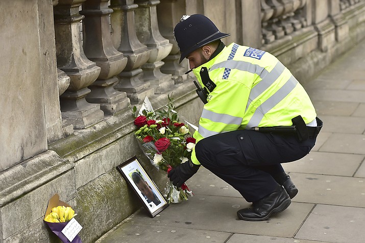 A police officer places flowers and a photo of fellow police officer Keith Palmer, who was killed in yesterdays attack, on Whitehall near the Houses of Parliament in London, Thursday March 23, 2017. On Wednesday a knife-wielding man went on a deadly rampage, first driving a car into pedestrians then stabbing a police officer to death before being fatally shot by police within Parliament's grounds in London.