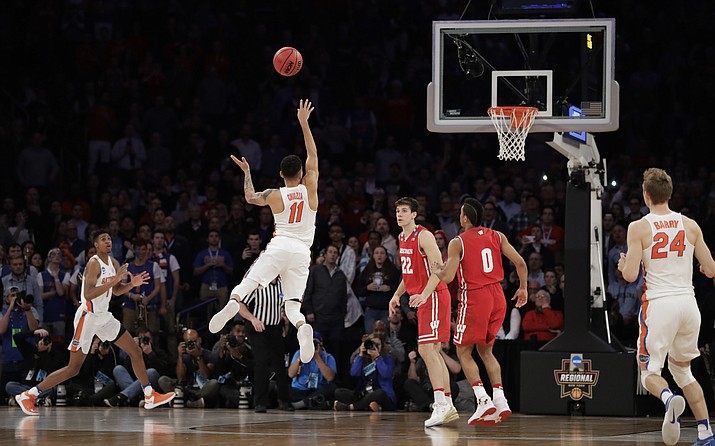 Florida guard Chris Chiozza (11) puts up a last second 3-point shot to score the game-winning points against Wisconsin in overtime of an East Regional semifinal game of the NCAA men’s college basketball tournament Saturday, March 24, in New York. Florida won 84-83. (Julio Cortez/AP)