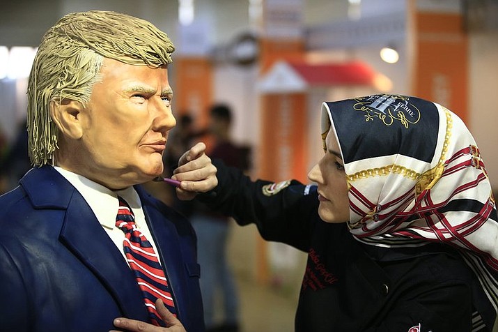 Turkish pastry chef Tuba Geckil adds the finishing touches to her figure of US President Donald Trump made out of cake icing which she created in two days, during a chocolate show in Istanbul, Saturday, March 25, 2017.