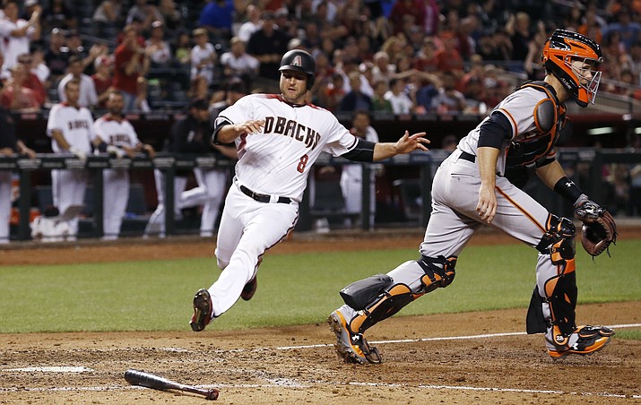 Arizona Diamondbacks’ Chris Iannetta (8) gets ready to slide into home plate to score a run as San Francisco Giants’ Buster Posey, right, moves up to make a catch on a late throw during the sixth inning Wednesday, April 5, in Phoenix. (Ross D. Franklin/AP)