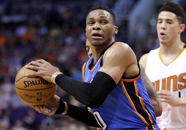 Oklahoma City Thunder guard Russell Westbrook (0) spins around Phoenix Suns guard Devin Booker during the first half Friday, April 7, in Phoenix. (Matt York/AP)